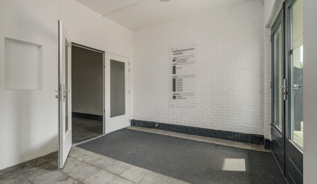 Ingang van een bedrijfsverzamelgebouw aan de Mercuriusweg met witte muren, glazen deuren en een bord met bedrijfsnamen.