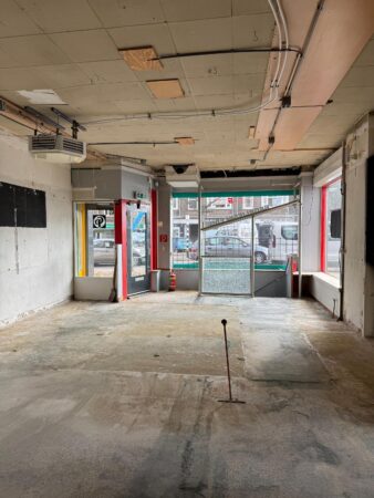 Leegstaand winkelpand aan de Prinses Mariannelaan met zicht op de straat door de glazen pui.