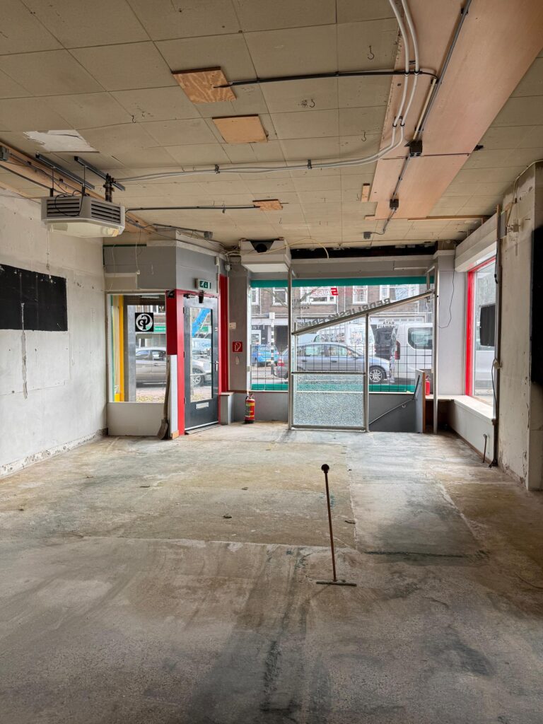 Leegstaand winkelpand aan de Prinses Mariannelaan met zicht op de straat door de glazen pui.