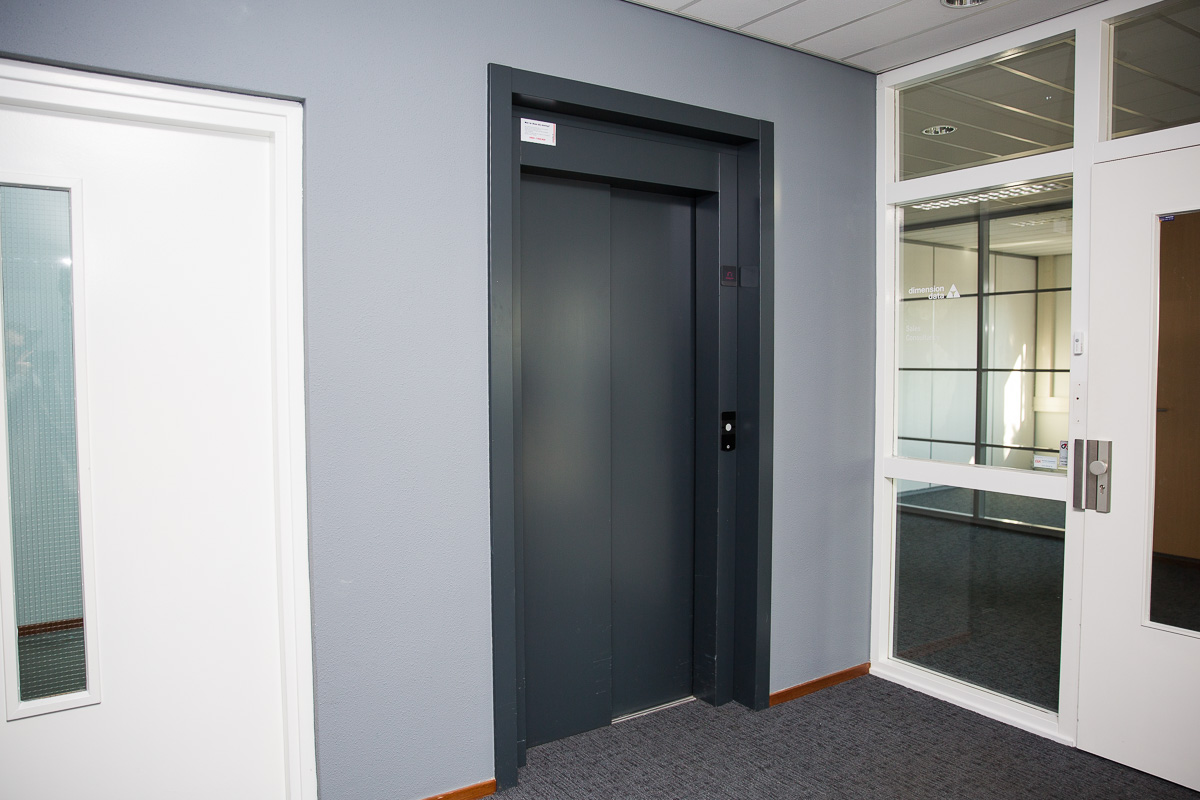 Grijze liftdeur in een modern kantoorpand aan de Laan van s-Gravenmade.