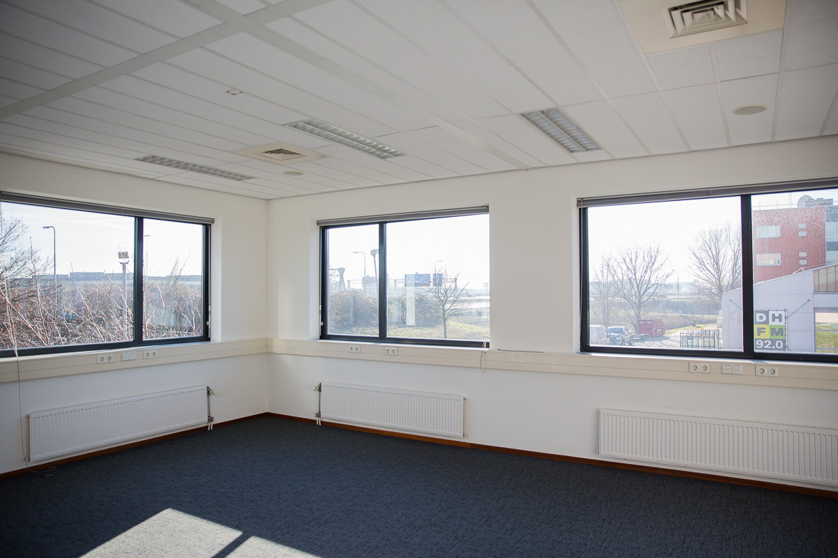 Lichte, lege kantoorruimte aan de Laan van 's-Gravenmade met grote ramen en uitzicht op buiten.
