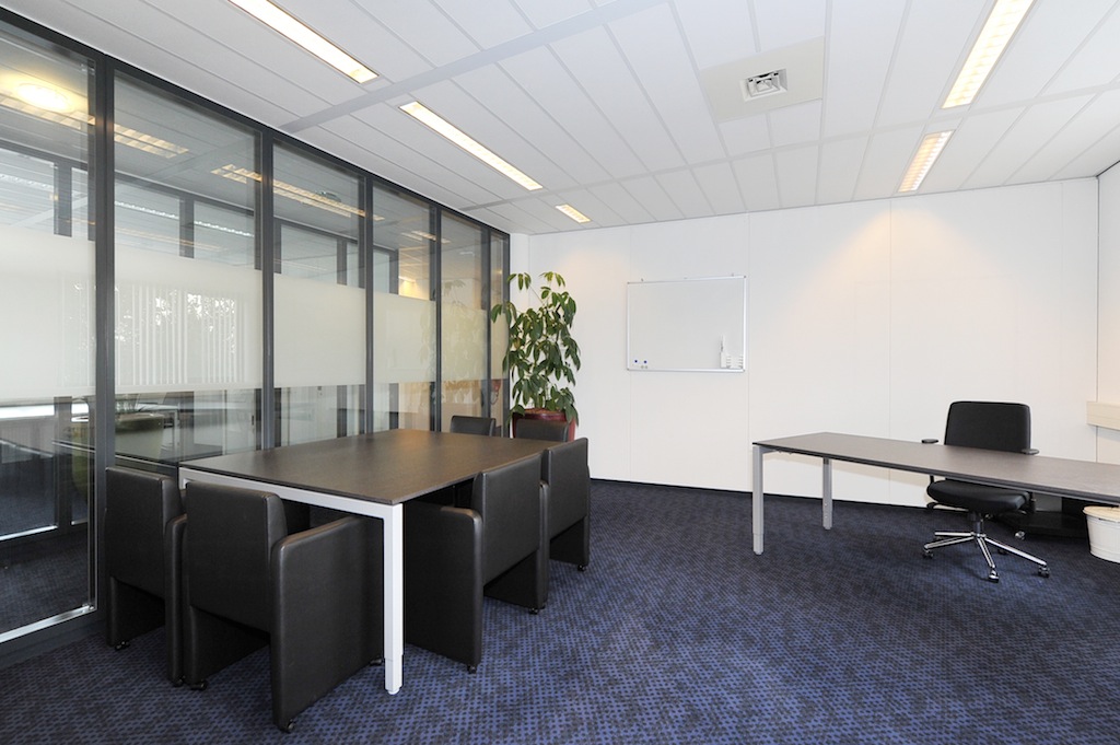 Moderne kantoorruimte aan de Laan van s-Gravenmade met vergadertafel, bureau, glazen wand en een whiteboard.
