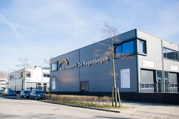 Bedrijfsgebouw van Businesspark De Regenboog aan de Laan van ’s-Gravenmade met geparkeerde auto's langs de straat.