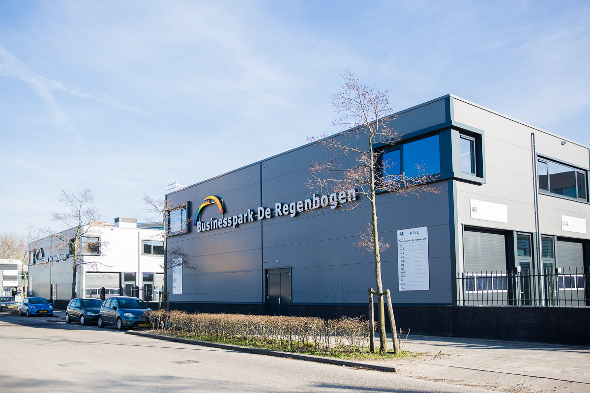 Bedrijfsgebouw van Businesspark De Regenboog aan de Laan van ’s-Gravenmade met geparkeerde auto's langs de straat.