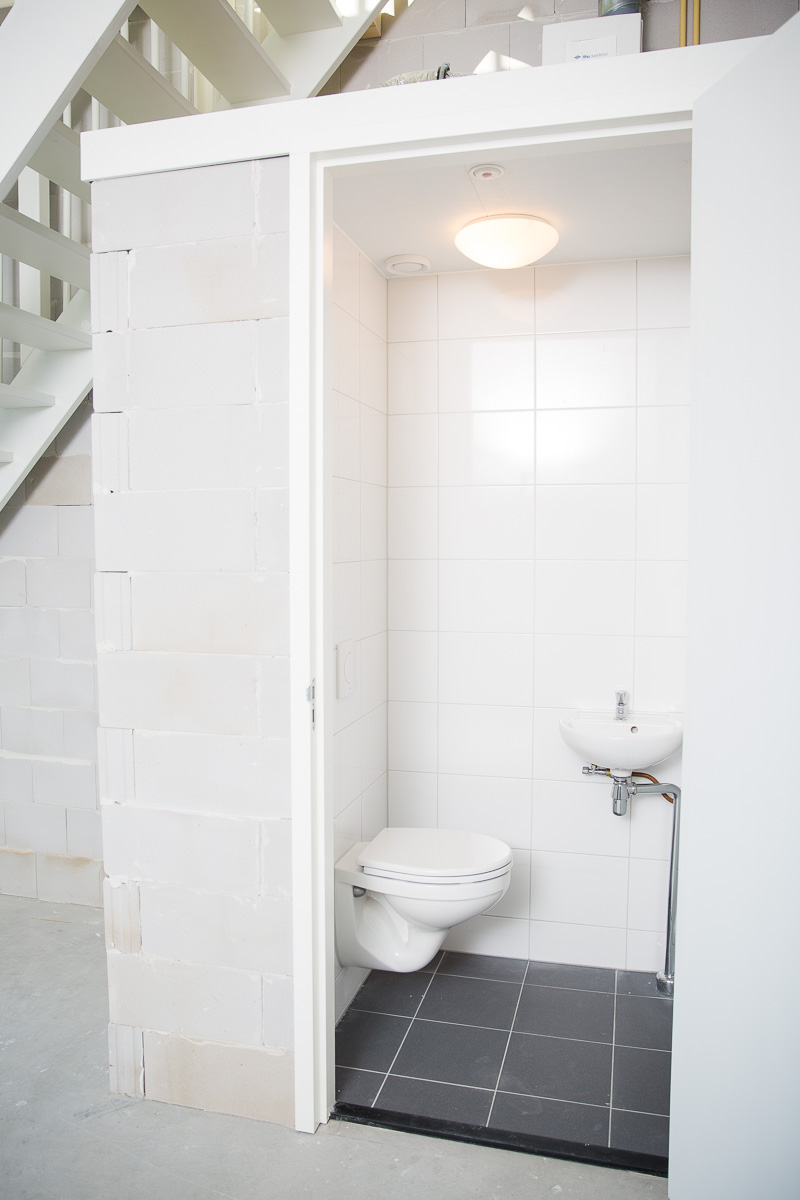 Kleine, witte toiletruimte met hangtoilet en fontein, gelegen onder een trap in een casco ruimte aan de Laan van S-Gravenmade.
