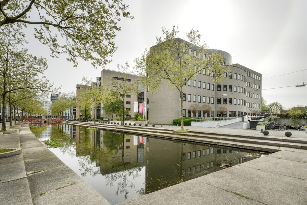 Kantoorgebouw aan de Euclideslaan in Utrecht met een gracht en bomen op de voorgrond.