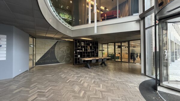 Moderne kantoorentree aan de Euclideslaan met glazen wanden, houten visgraatvloer en een open vergaderruimte.