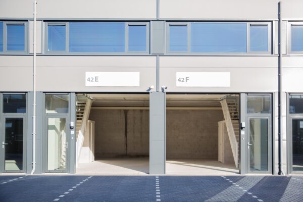 Twee lege bedrijfsunits met huisnummers 42E en 42F aan de Laan van s-Gravenmade, met glazen entreedeuren en interne trappen.