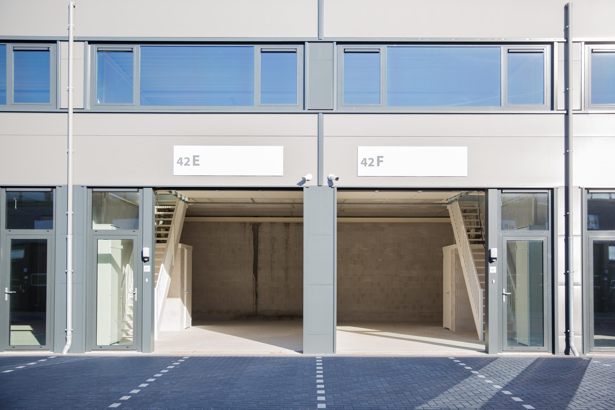 Twee lege bedrijfsunits met huisnummers 42E en 42F aan de Laan van s-Gravenmade, met glazen entreedeuren en interne trappen.