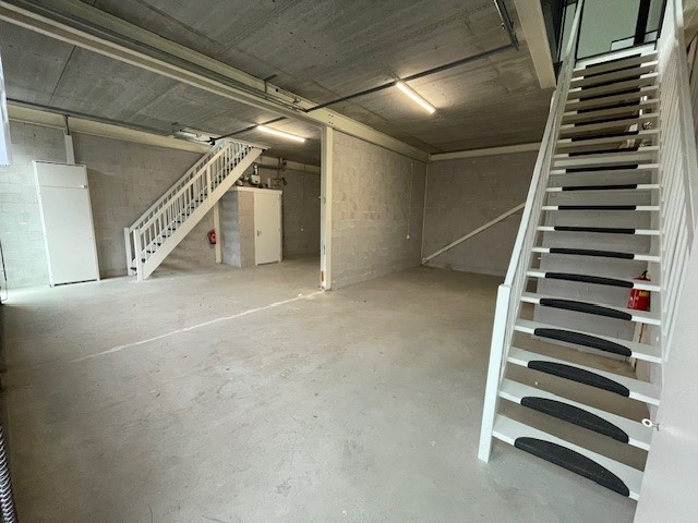 Leeg industrieel bedrijfsunit aan de Laan van ’s-Gravenmade met betonnen vloer, zichtbare leidingen en twee witte trappen naar de bovenverdieping.