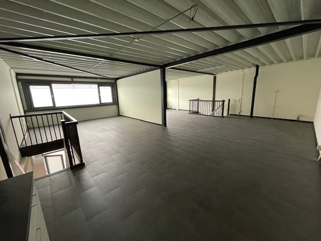 Leeg industrieel kantoorpand aan de Laan van ’s-Gravenmade met donkergrijze vloer en zichtbare plafondbalken.