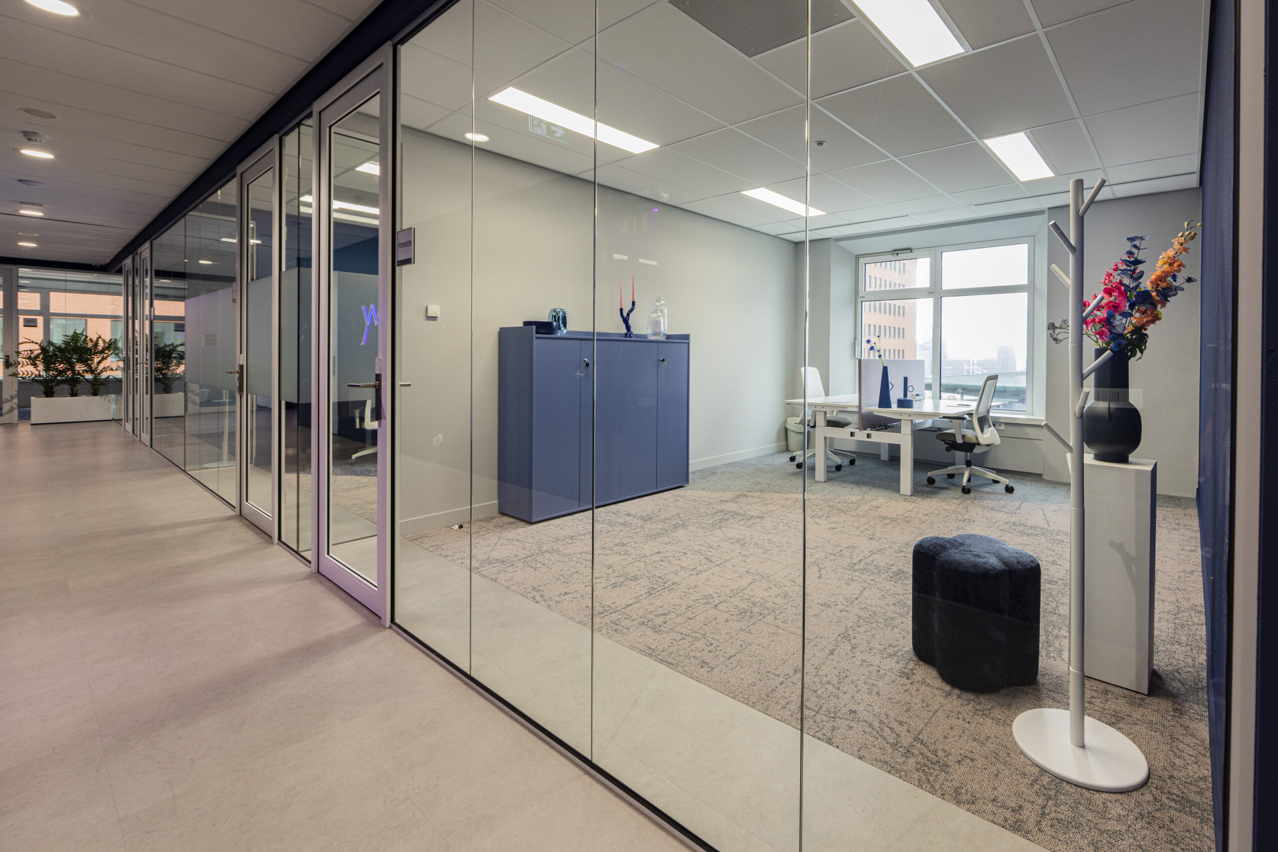 Een modern en strak ingericht kantoorpand in Rotterdam met glazen wanden en kleurrijke bloemen.