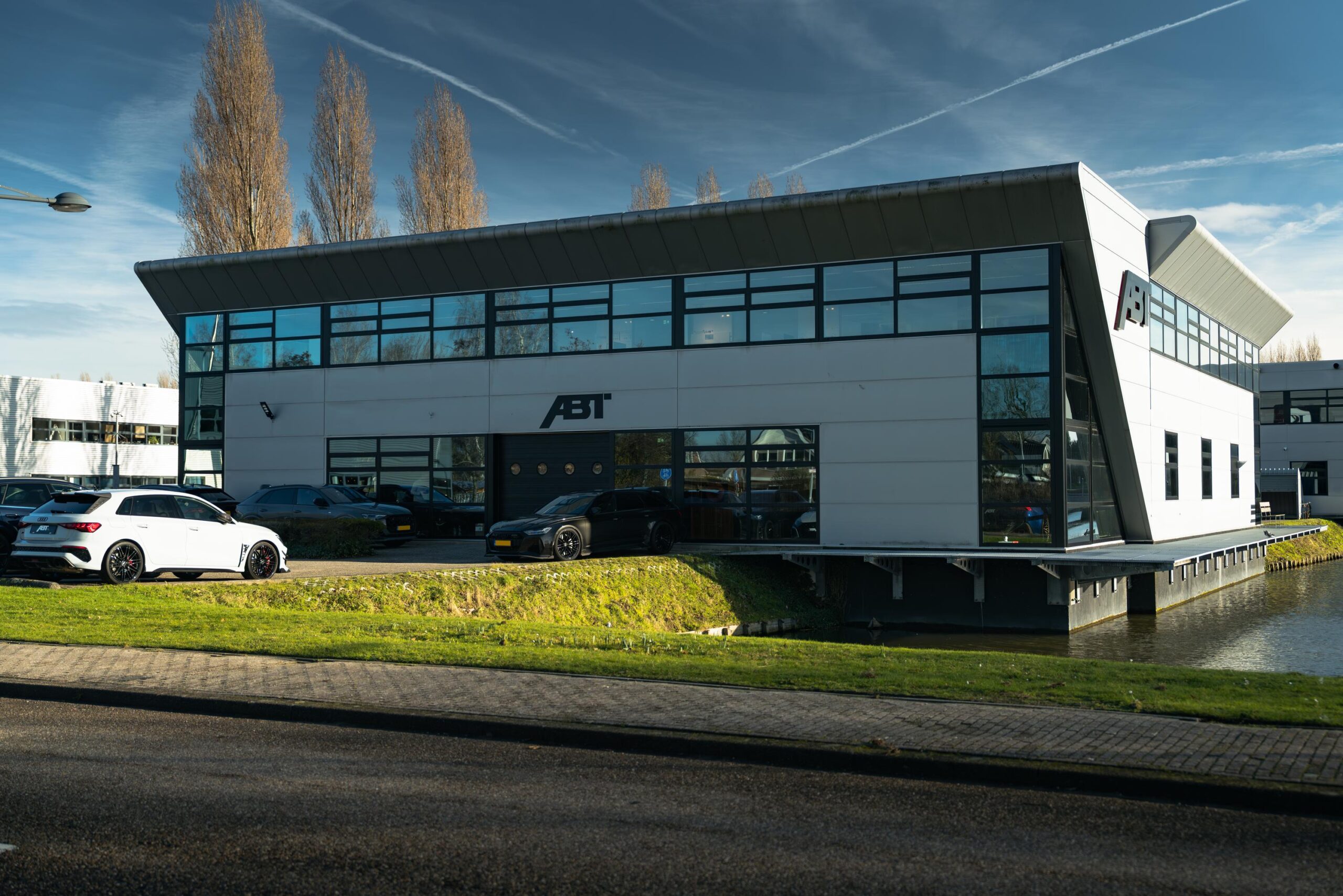 Modern bedrijfsgebouw van ABT aan de Frankfurtstraat met geparkeerde auto's ervoor.