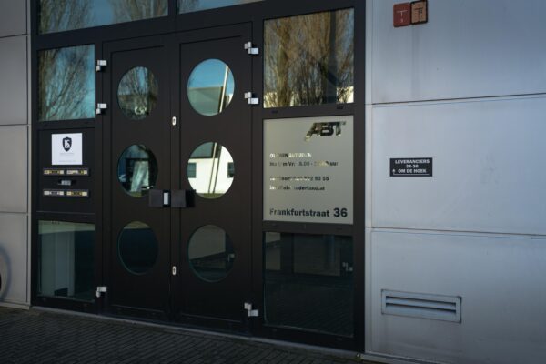 Ingang van een bedrijfsgebouw aan de Frankfurtstraat 36 met naam- en contactgegevens op de deur.