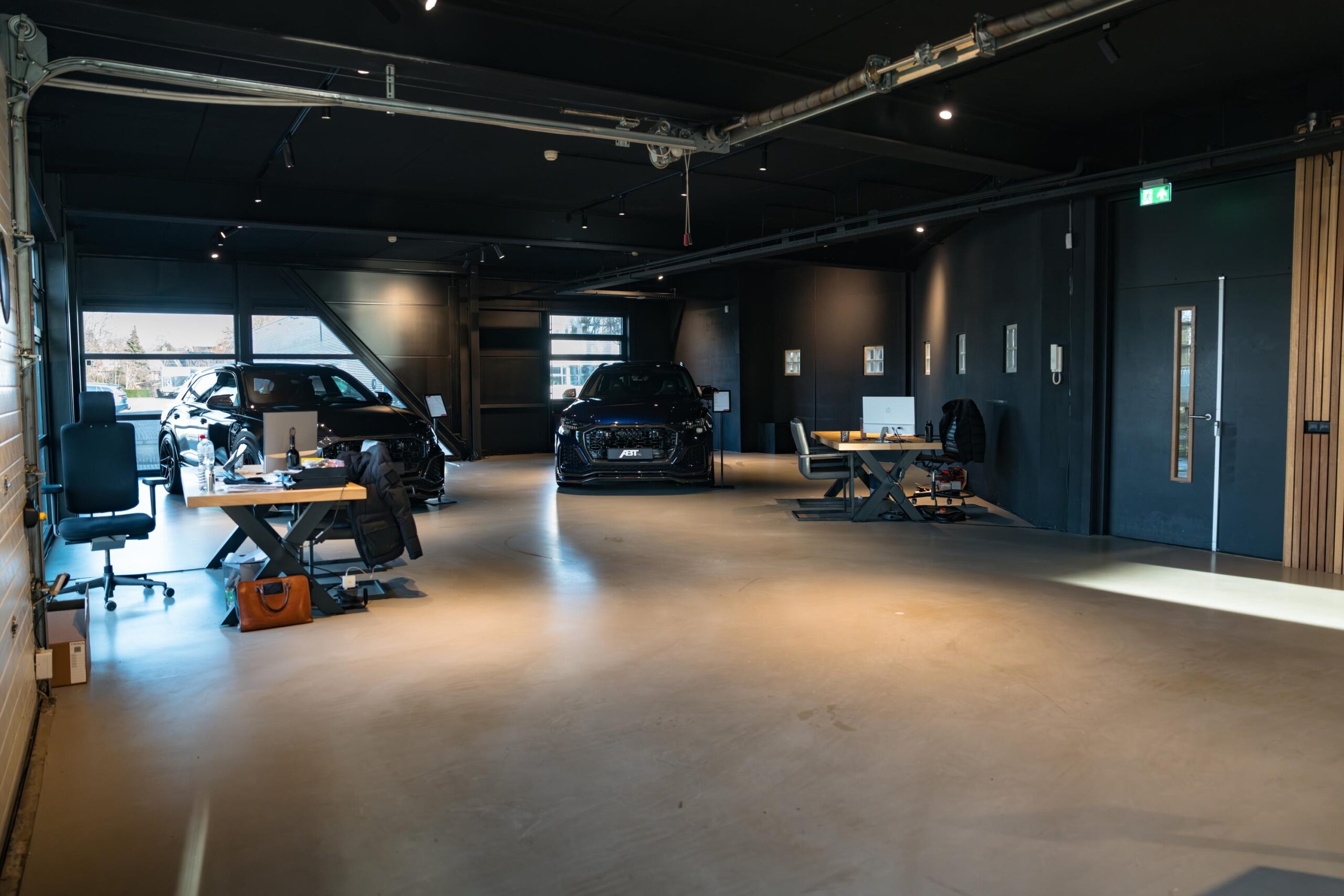 Moderne showroom aan de Frankfurtstraat met luxe auto’s en werkplekken in een stijlvolle, industriële ruimte.