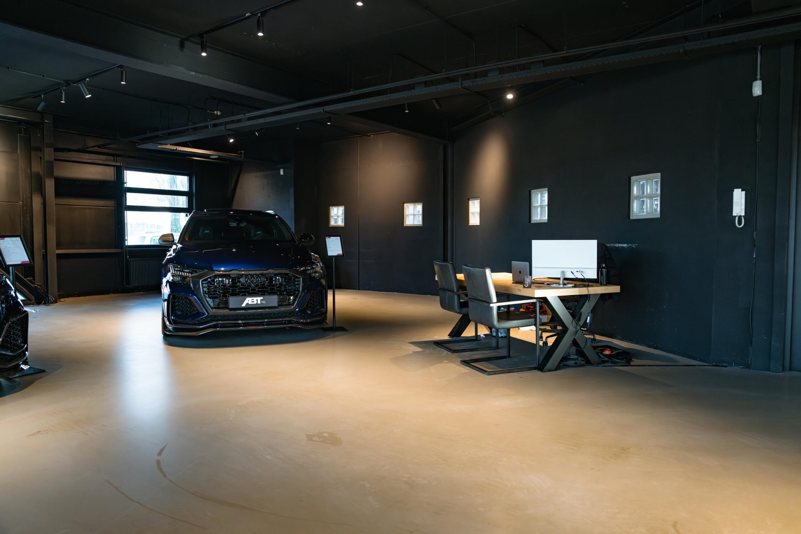 Moderne showroom aan de Frankfurtstraat met een zwarte ABT-auto en een stijlvol ingericht kantoorgedeelte.