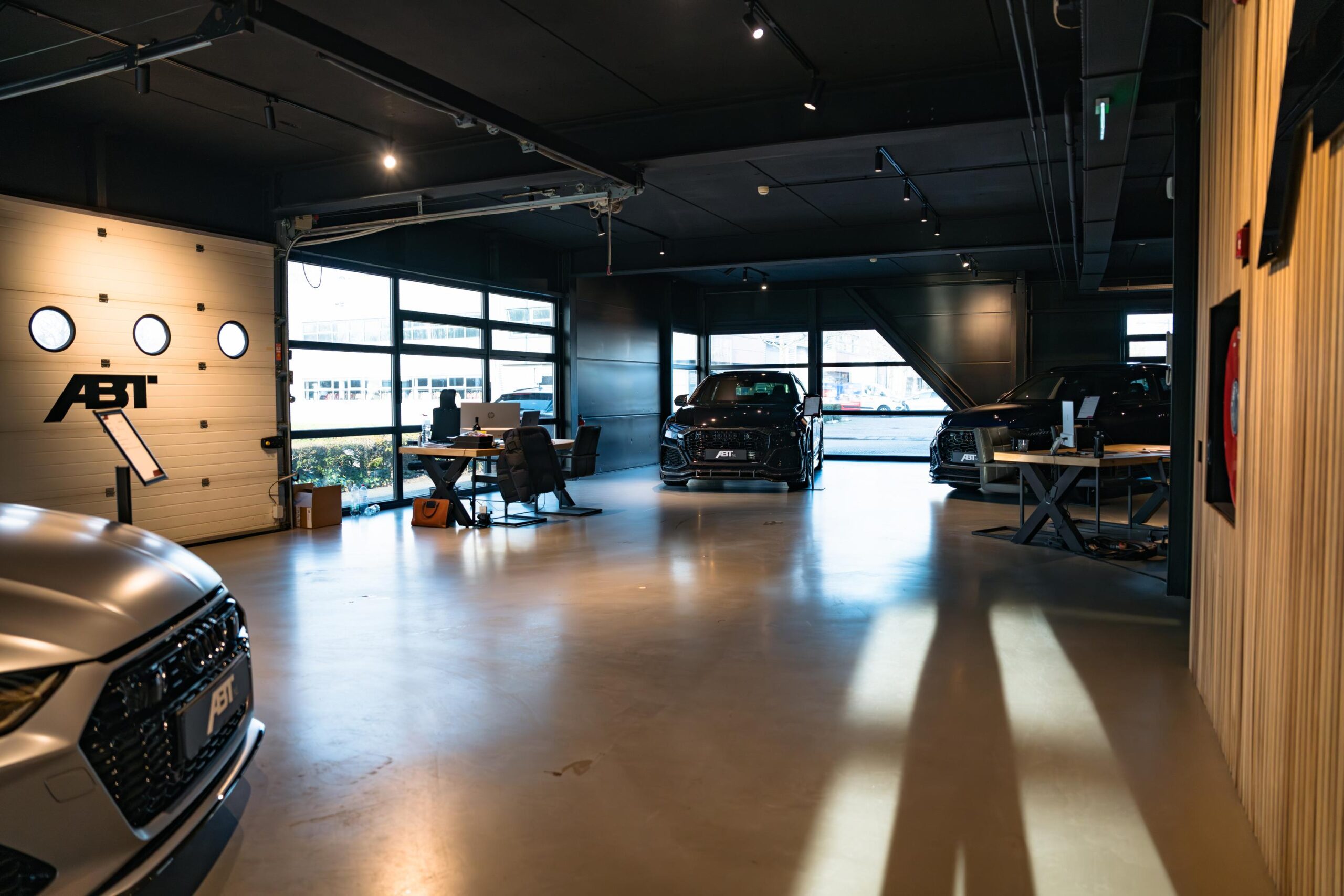 Moderne showroom aan de Frankfurtstraat met ABT-getunede Audi's en werkplekken in industriële stijl.