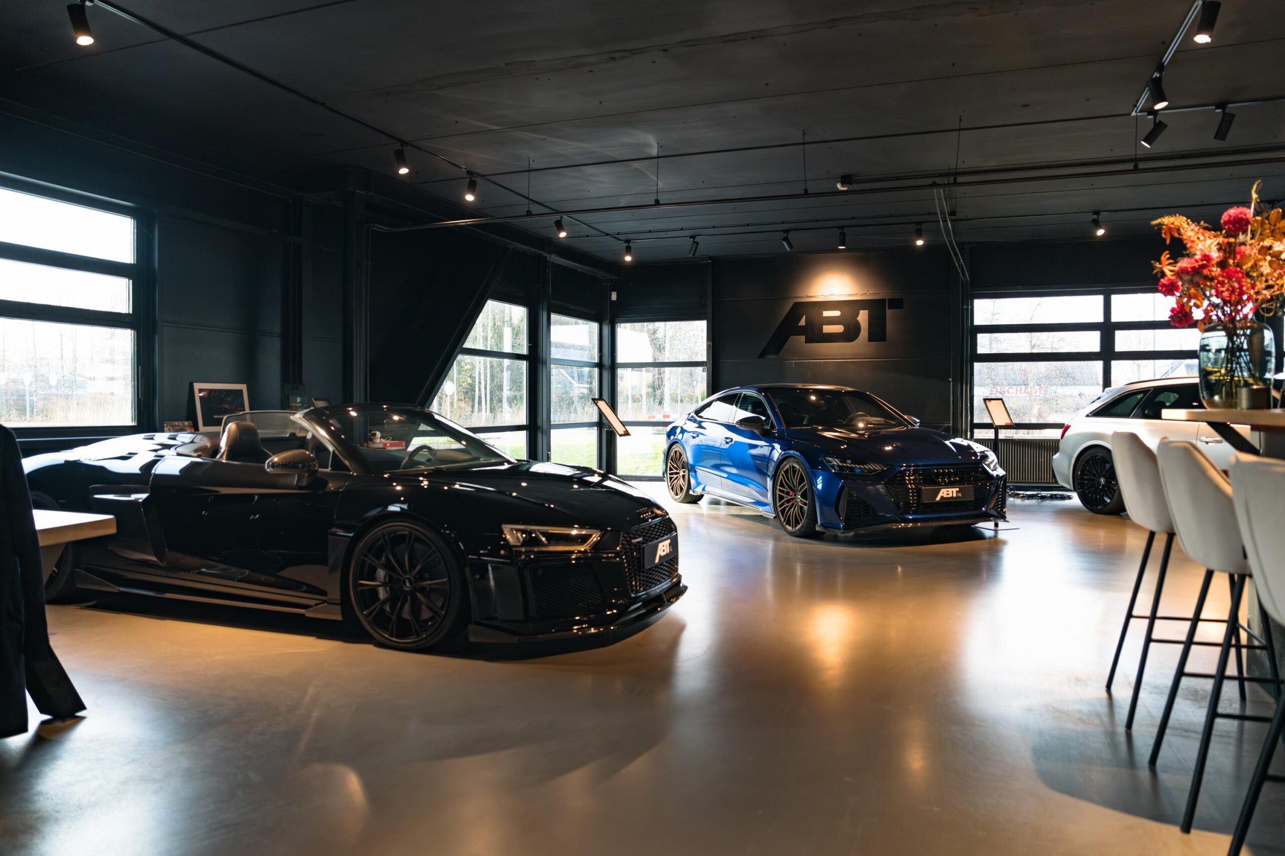 Showroom met luxe sportauto's van ABT Sportsline aan de Frankfurtstraat, inclusief een zwarte cabrio, een blauwe sedan en een witte stationwagen.