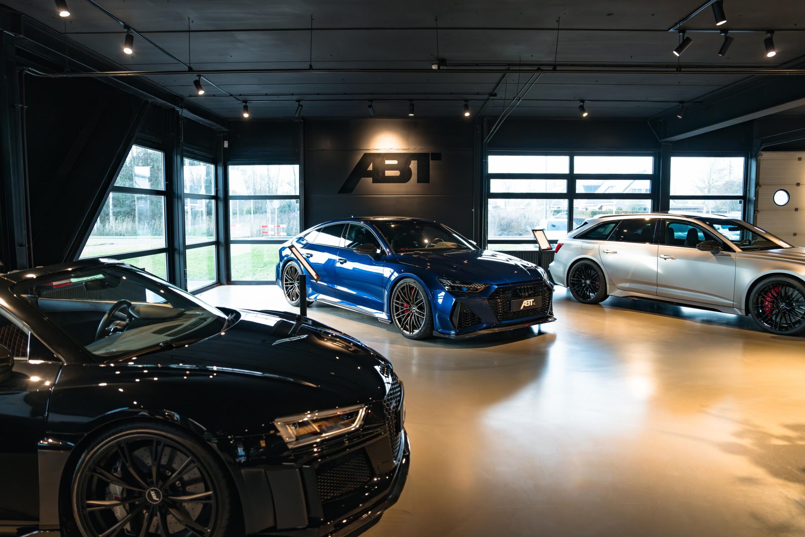 Drie sportieve ABT-getunede Audi's staan opgesteld in een moderne showroom aan de Frankfurtstraat.