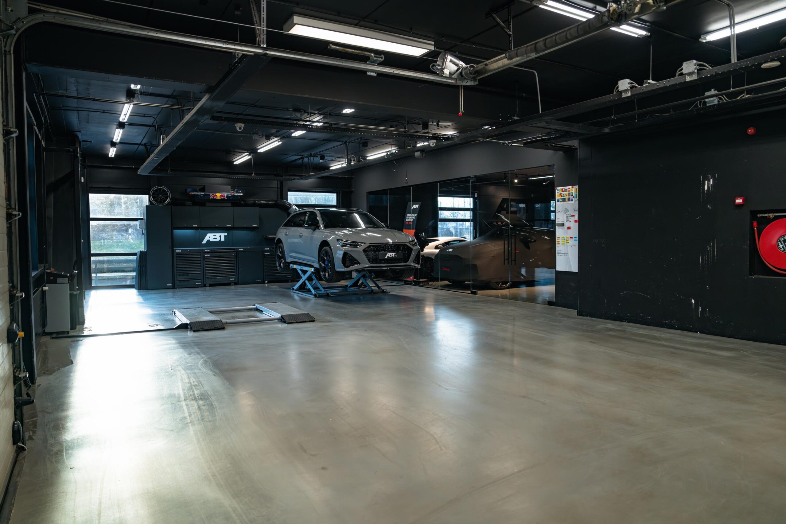 Moderne autowerkplaats aan de Frankfurtstraat met een grijze sportwagen op een autobrug bij de ABT-tuningafdeling.