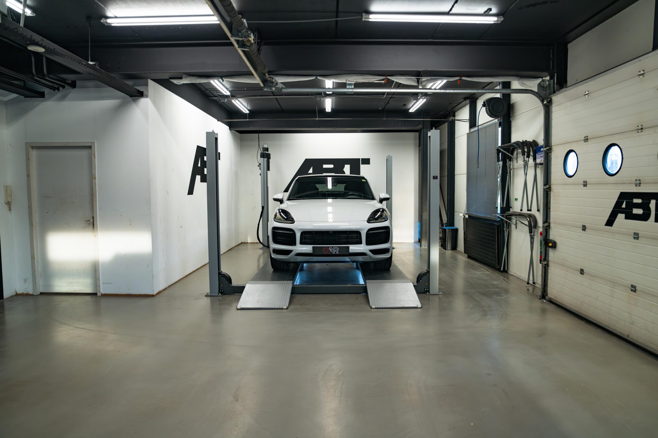 Witte sportieve SUV op een autobrug in een moderne werkplaats aan de Frankfurtstraat.