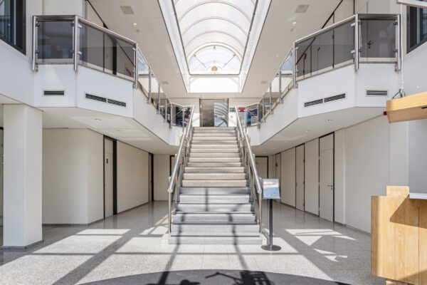Lichte en moderne ontvangsthal met centrale trap en glazen dak in een kantoorgebouw aan de Energieweg.