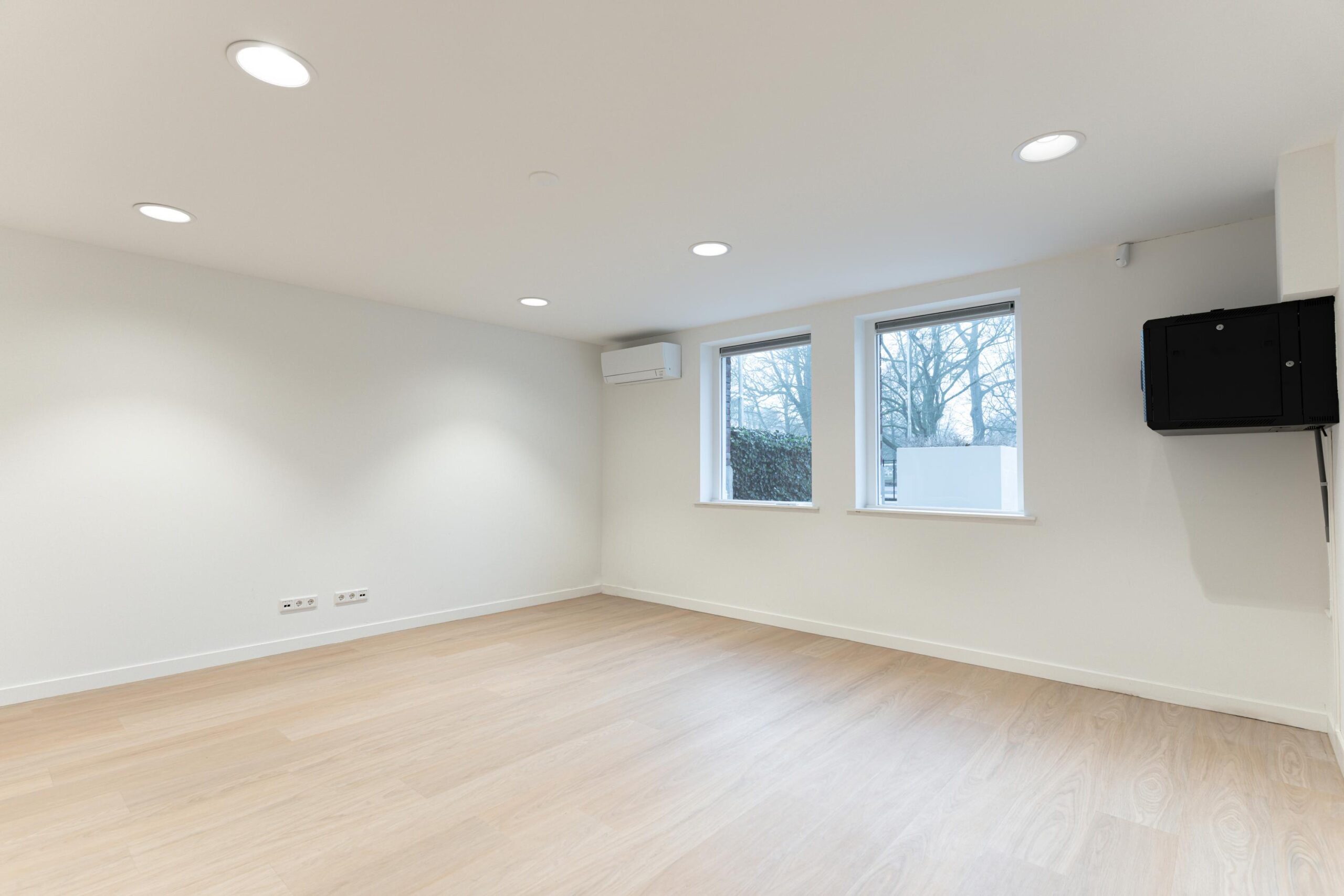 Lichte, lege kamer aan de Biltstraat met houten vloer, twee ramen, airco-unit en wandkast.