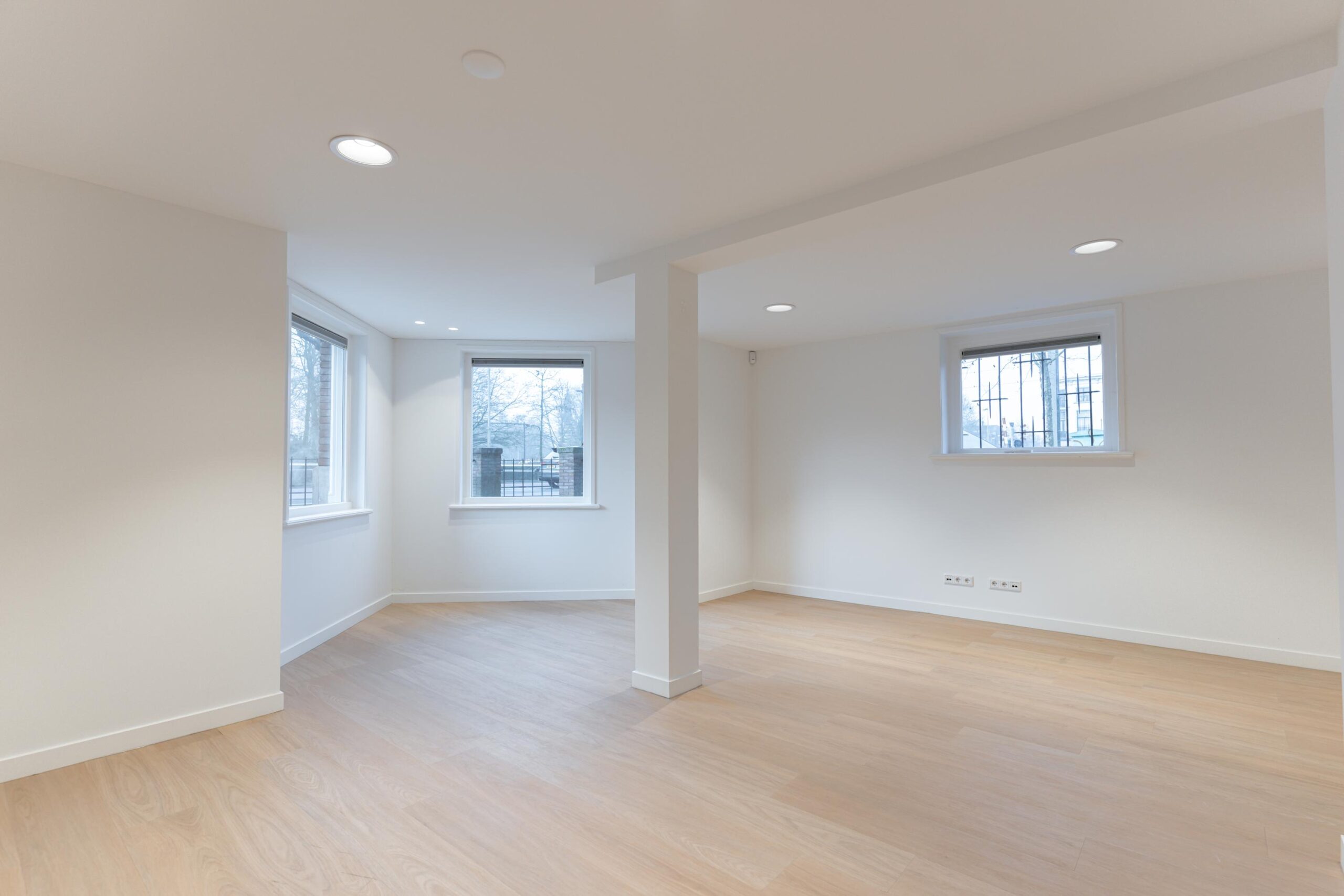 Lichte, lege kamer met grote ramen en een houten vloer aan de Biltstraat.