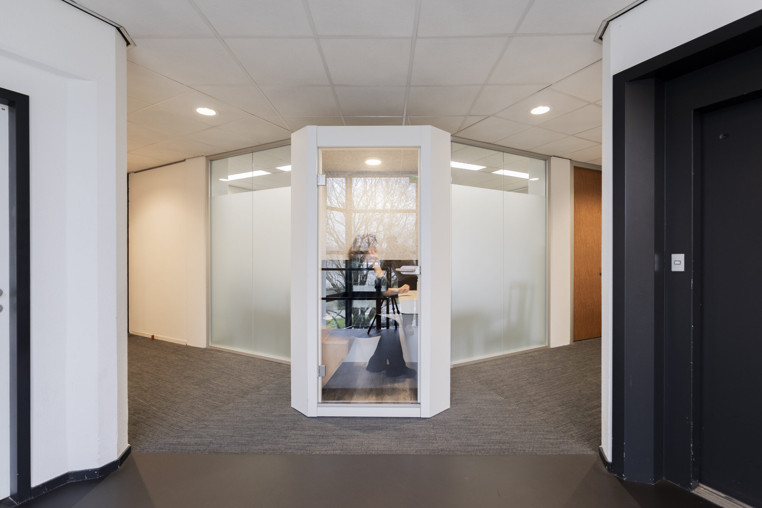 Een glazen belcel in een kantooromgeving aan de Winthontlaan met een persoon die binnen zit.