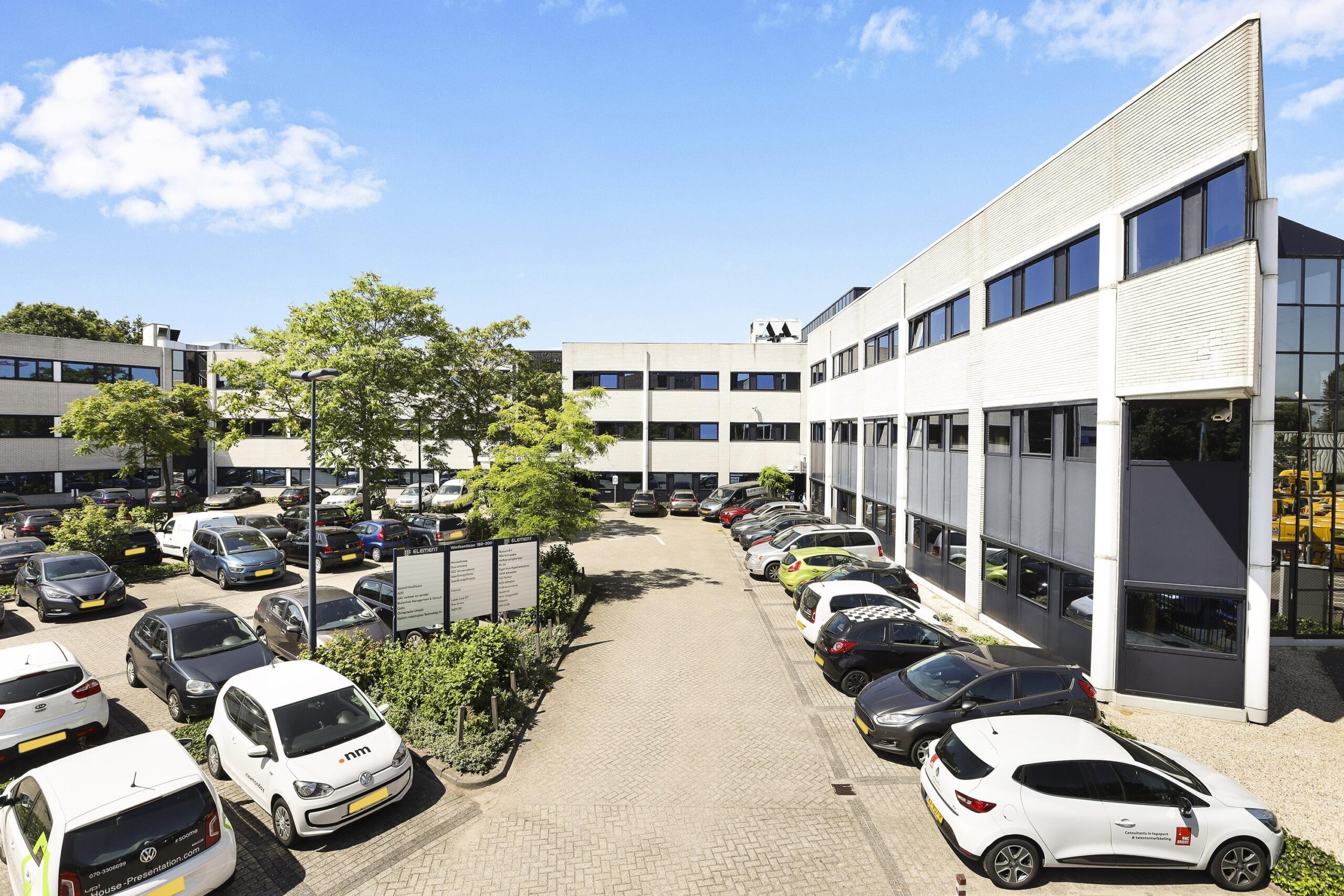 Een parkeerplaats vol auto's omringd door moderne kantoorgebouwen aan de Winthontlaan.