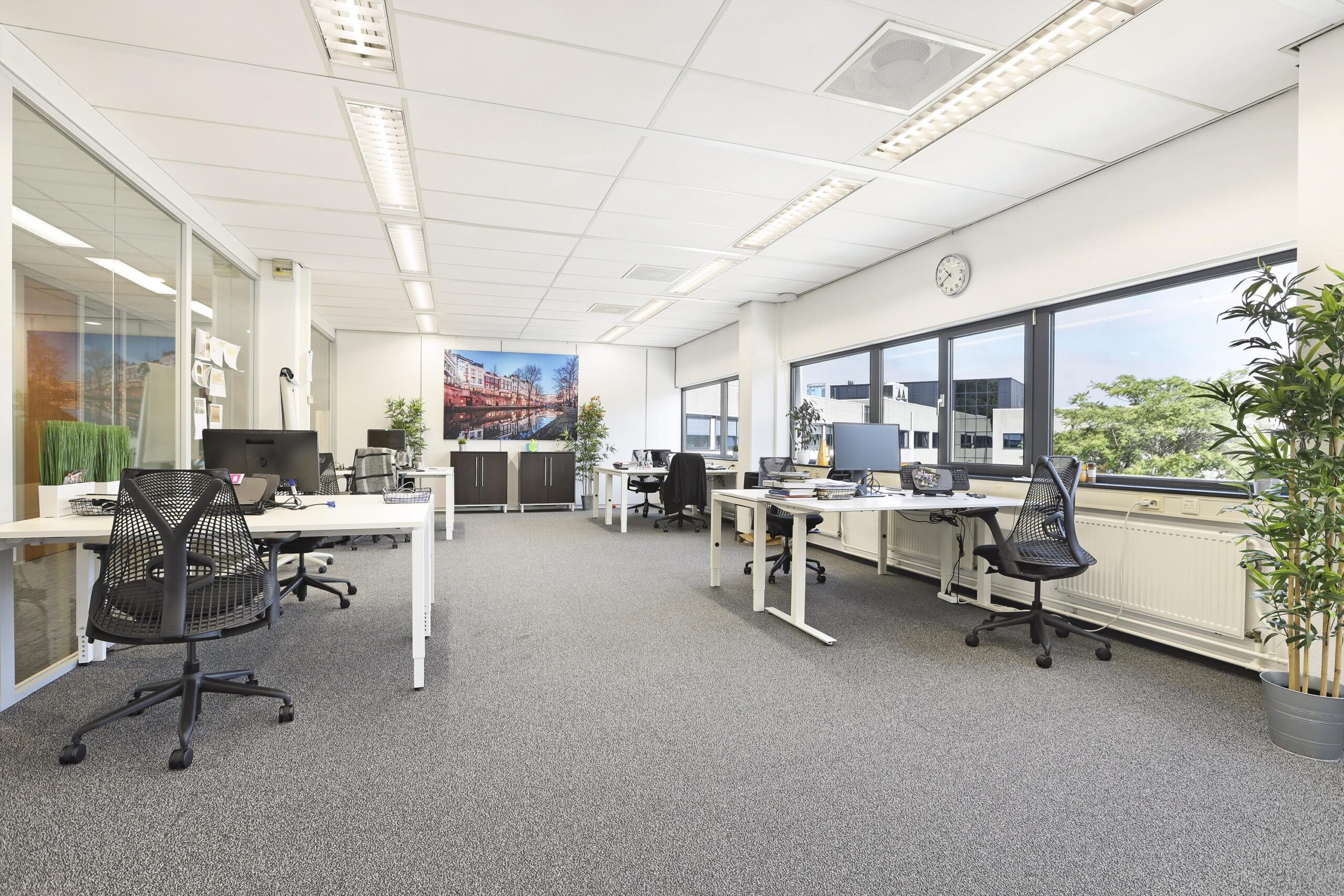 Een lichte en ruime kantoorruimte met bureaus, stoelen en grote ramen.