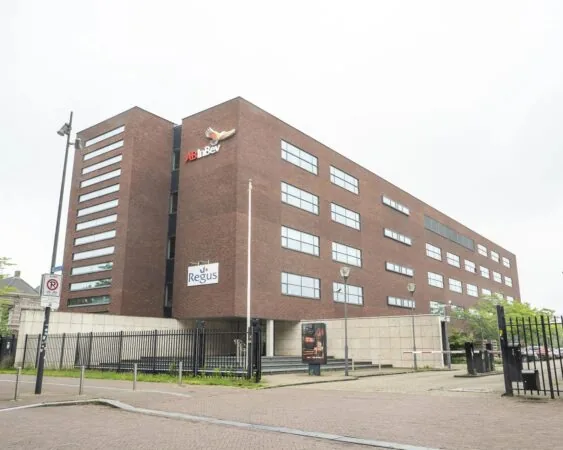 Kantoorgebouw met de logo’s van AB InBev en Regus op de gevel, gefotografeerd vanaf de straatzijde.