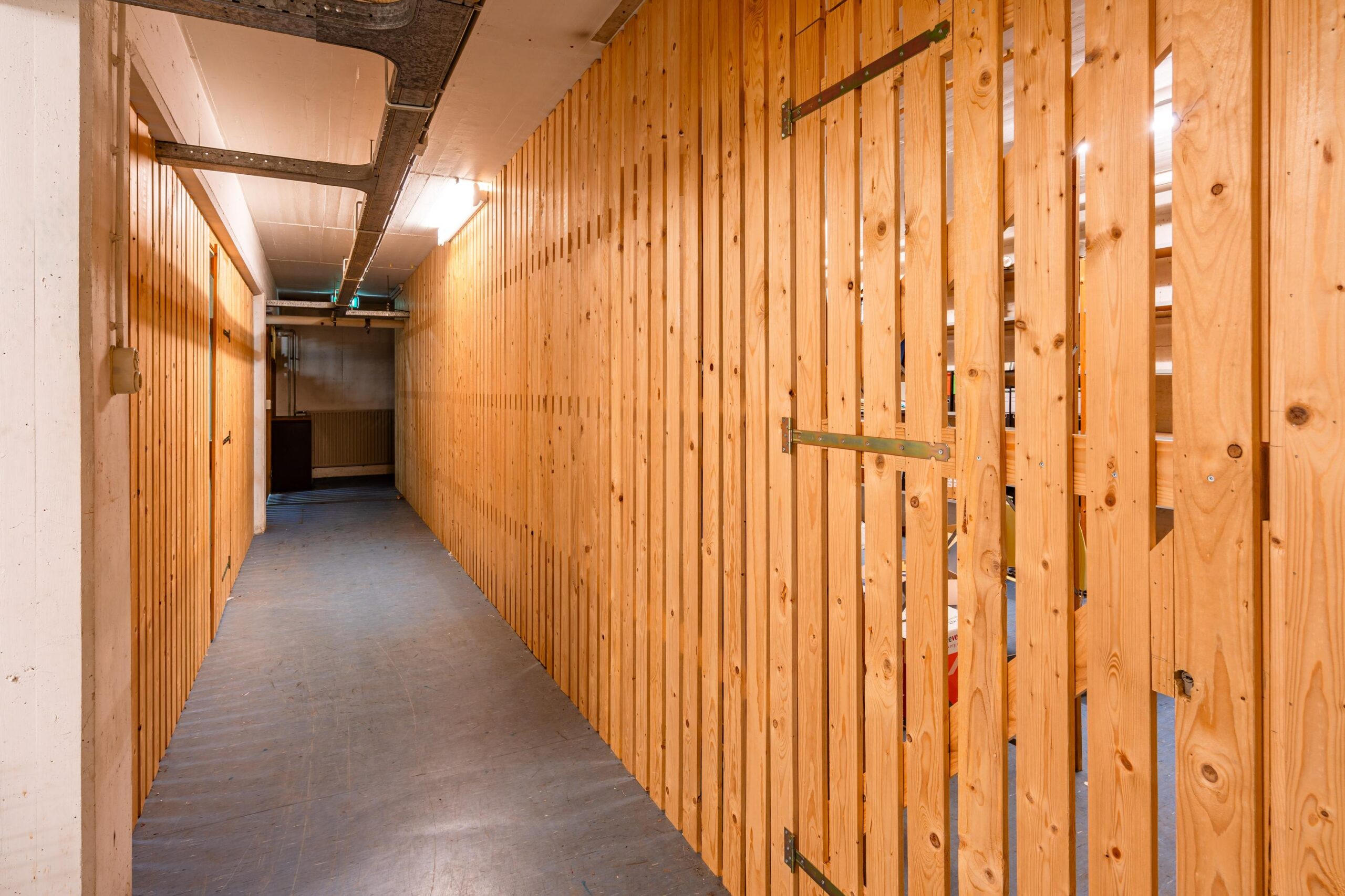 Een lange, smalle gang met houten latwerkpanelen aan de rechterkant in de Nicolaas Pieckstraat.