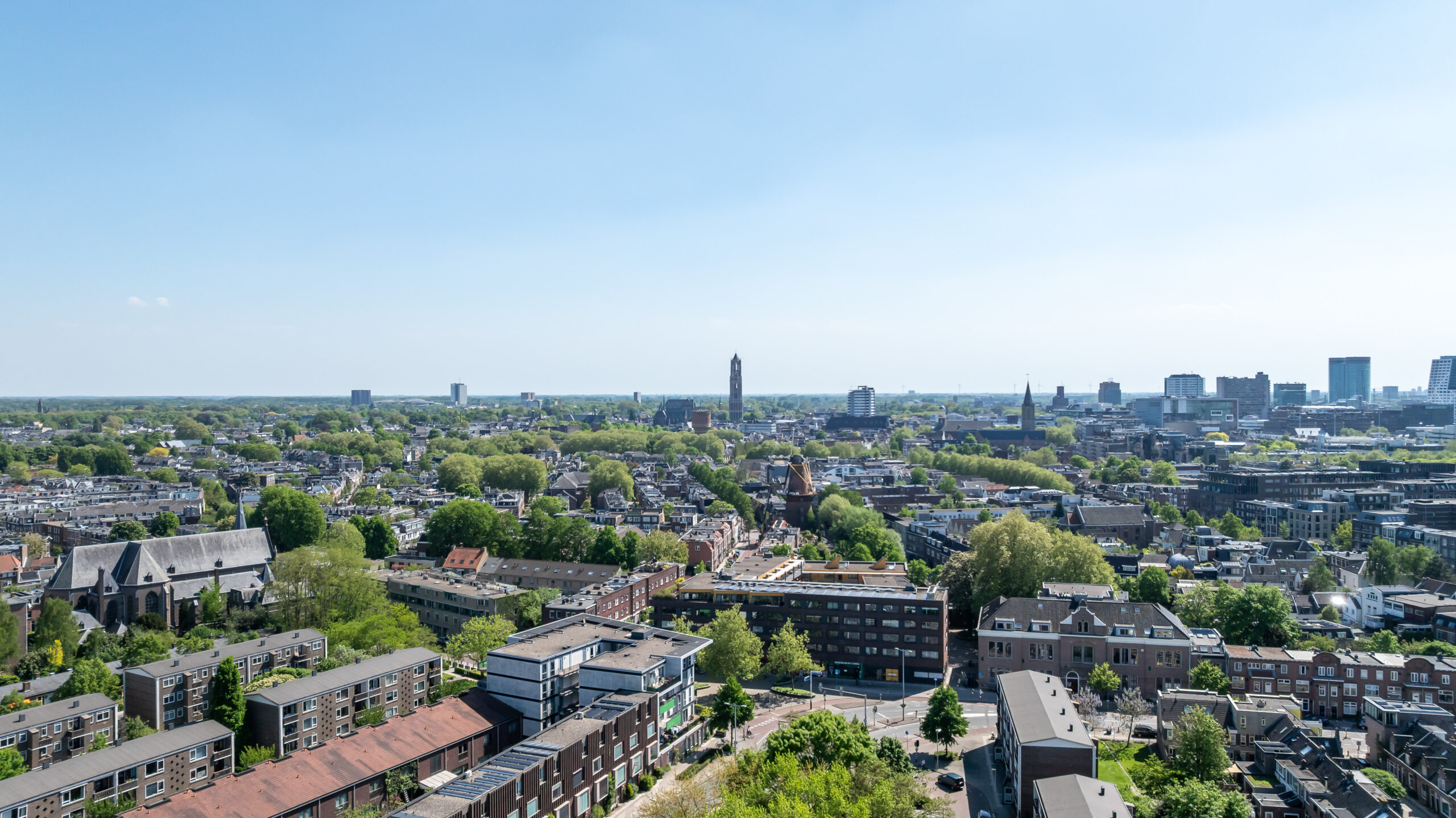 Luchtfoto van Utrecht met een panoramisch uitzicht op de stad, inclusief de Domtoren en groene gebieden.