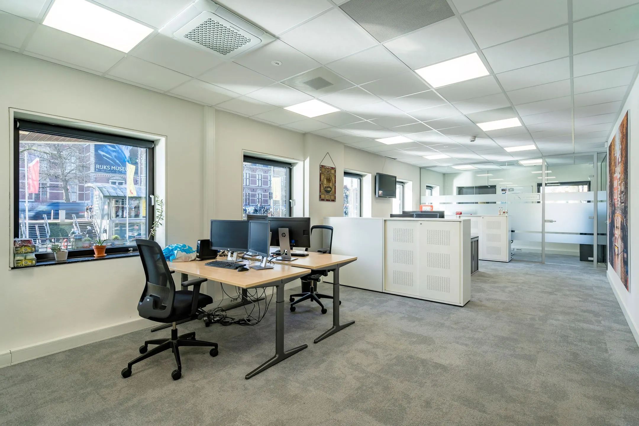 Moderne en lichte kantoorruimte met werkplekken, computers en uitzicht op het Rijksmuseum.