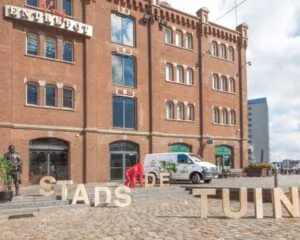 Bakstenen kantoorpand "Vijf Werelddelen 69" in Rotterdam met grote letters "STADSTUIN" op het plein ervoor.