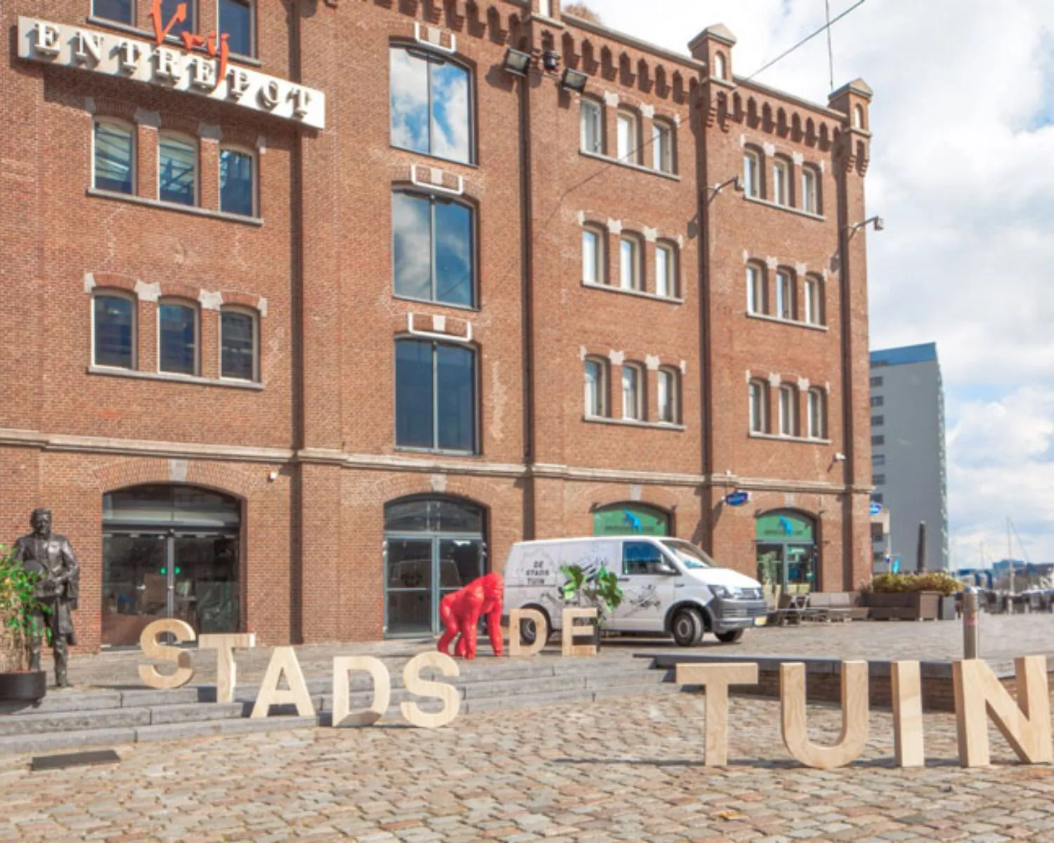 Bakstenen kantoorpand "Vijf Werelddelen 69" in Rotterdam met grote letters "STADSTUIN" op het plein ervoor.