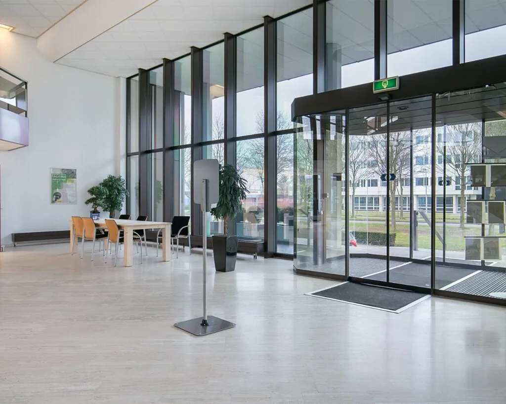 Moderne entreehal van een kantoorruimte aan de Bolderweg 1 in Almere met glazen schuifdeuren en zitgedeelte.