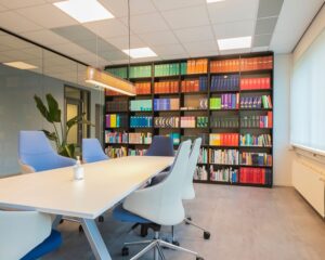 Moderne vergaderruimte aan de Bolderweg 2a in Almere met een lange witte tafel, designstoelen en een grote boekenkast gevuld met gekleurde ordners en boeken.