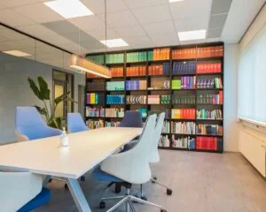 Moderne vergaderruimte aan de Bolderweg 2a in Almere met een lange witte tafel, designstoelen en een grote boekenkast gevuld met gekleurde ordners en boeken.