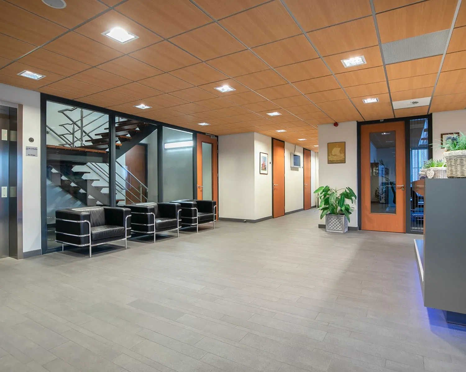 Moderne entreehal van een kantoorruimte aan de Carlsonstraat 13 in Kampen met zithoek, planten en houten plafond.