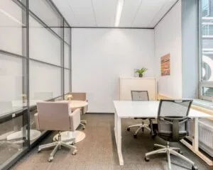 Moderne kantoorruimte met glazen wand, twee bureaus en vergadertafel in Flight Forum 40 in Eindhoven.