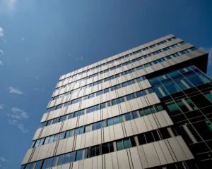 Modern kantoorgebouw aan de Herikerbergweg 288-290 in Amsterdam tegen een helderblauwe lucht.