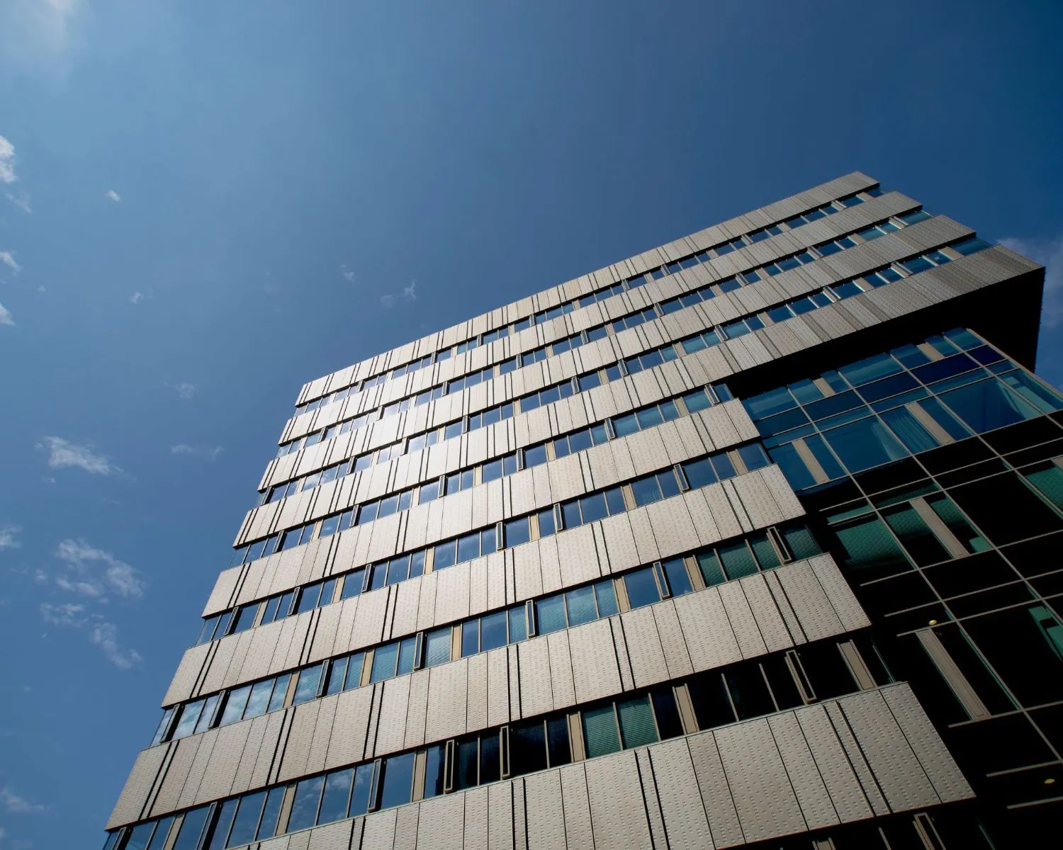 Modern kantoorgebouw aan de Herikerbergweg 288-290 in Amsterdam tegen een helderblauwe lucht.