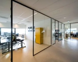 Moderne kantoorruimte met glazen wanden en een opvallende gele kast in Rietlandpark 303, Amsterdam.