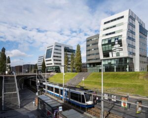 Modern kantoorgebouw aan het Rietlandpark in Amsterdam met een tramhalte op de voorgrond.