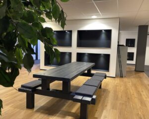 Moderne kantoorruimte in Elisabethhof Leiderdorp met houten vloer, zwarte picknicktafel en ingebouwde schermen aan de muur.