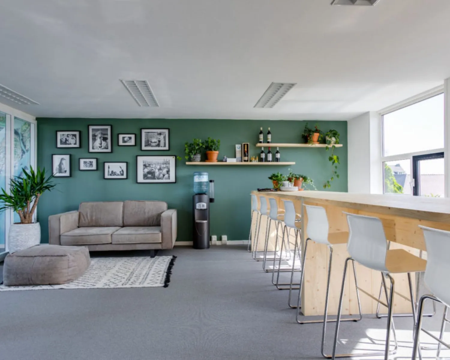 Moderne kantoorruimte aan de Wilhelminastraat 43A in Haarlem met loungehoek, barzitjes en groene accenten.
