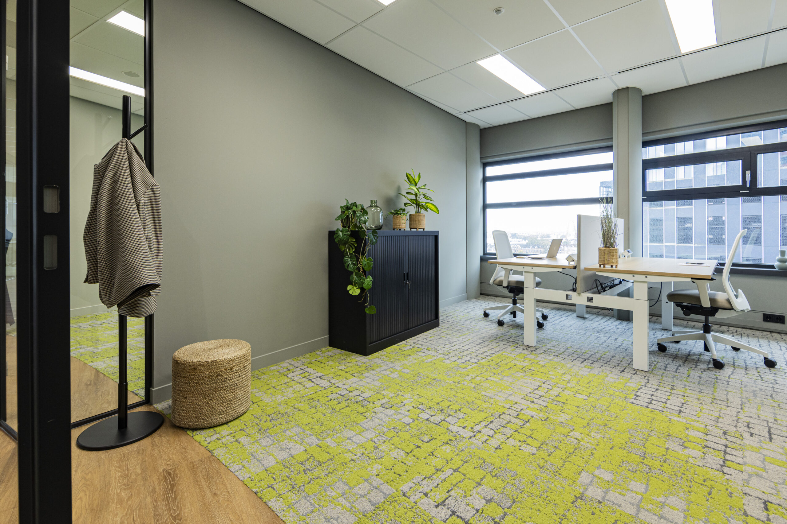 Een modern kantoor in Rotterdam met planten, een bureaustoel en een groen gevlekt tapijt.