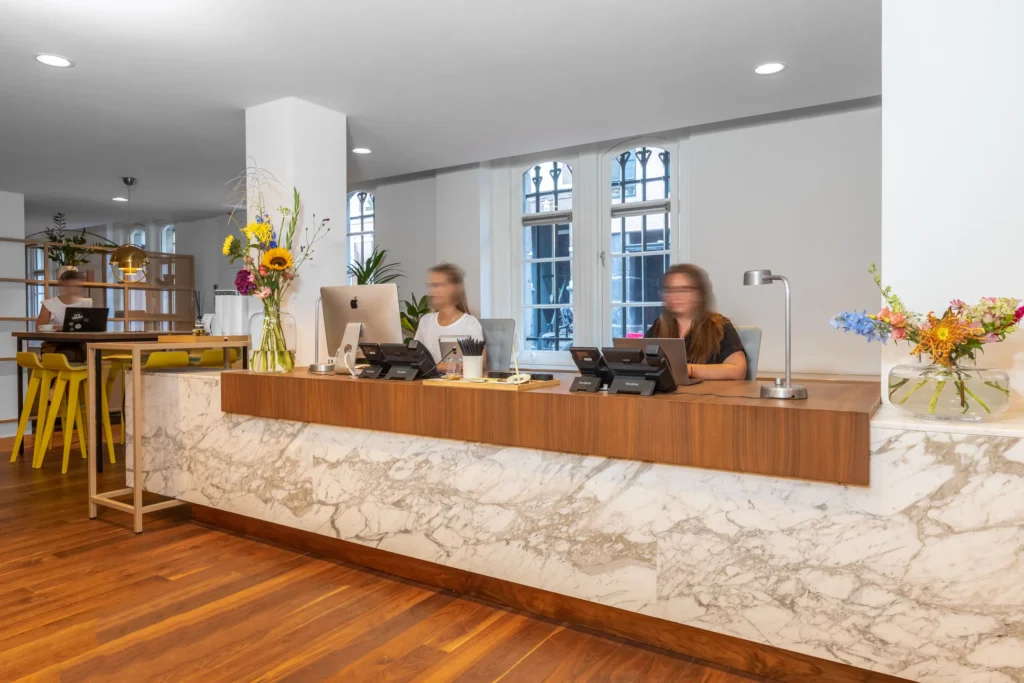 Receptiebalie met medewerkers en een stijlvolle marmeren afwerking in een modern kantoorinterieur.